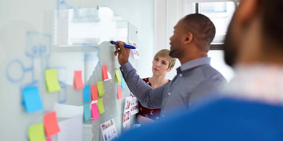 instructor teaching using a whiteboard with sticky notes