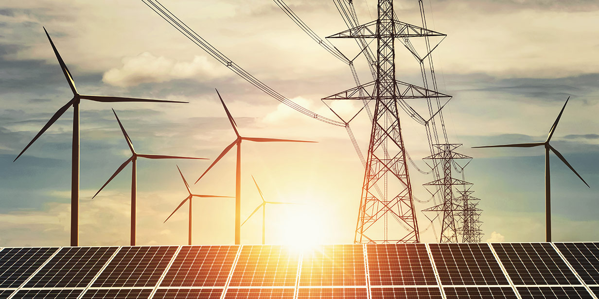 Wind turbines, power transmission lines and solar panels lit by the sun.