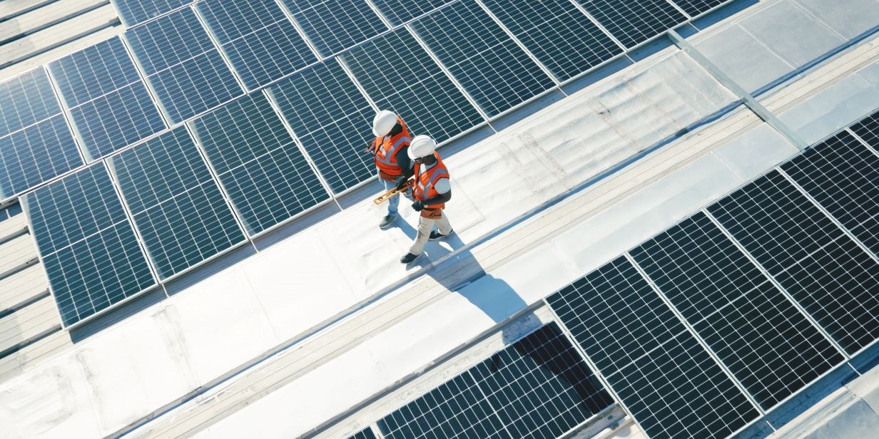 Renewable energy, solar panels and team walking on roof planning for inspection at sustainable business. Engineering, sustainability and photovoltaic power on rooftop, men in electricity maintenance.
