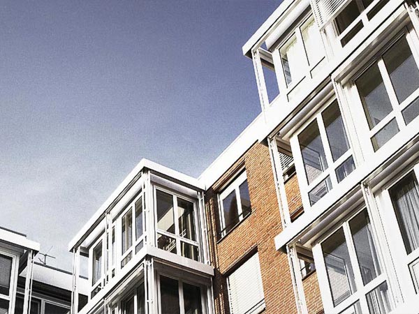 Modern residential building with large windows and brick facade under a clear blue sky