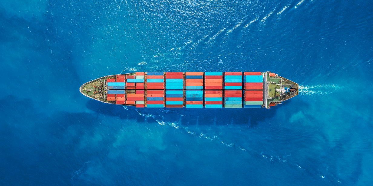 cargo ship transporting colorful shipping containers across deep blue ocean waters, viewed from above