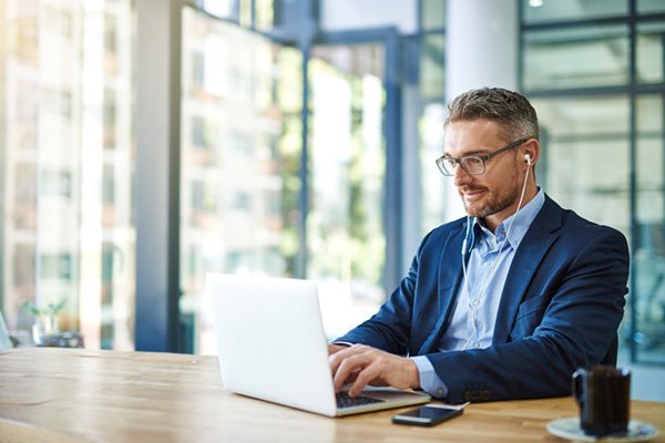 person in business attire using a laptop in a modern office