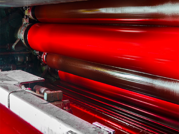 close-up of printing press with red ink rollers in operation