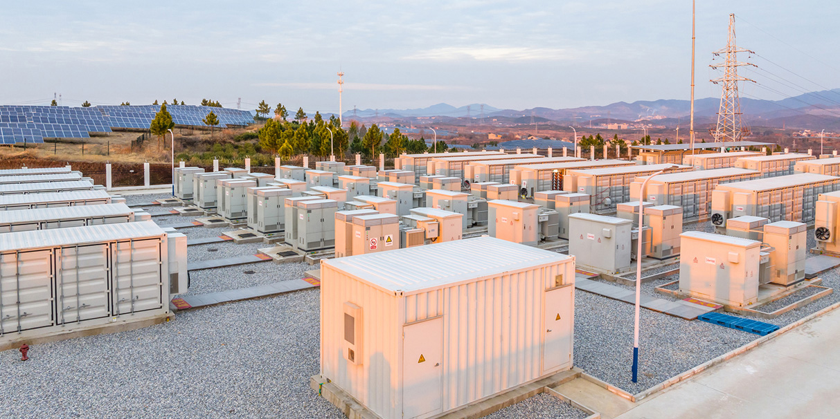 battery energy storage system (BESS) connected to a solar energy facility, featuring containerized lithium-ion battery units, electrical infrastructure, and power grid connections