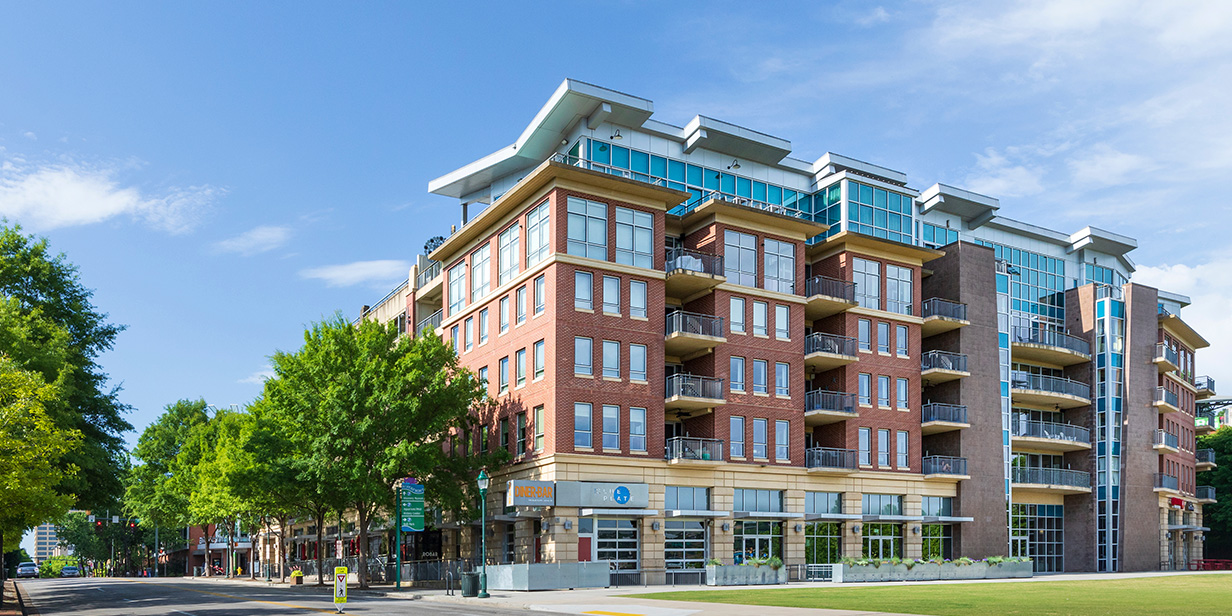 modern mixed-use apartment building with brick and glass façade, multiple balconies, and ground-floor commercial space