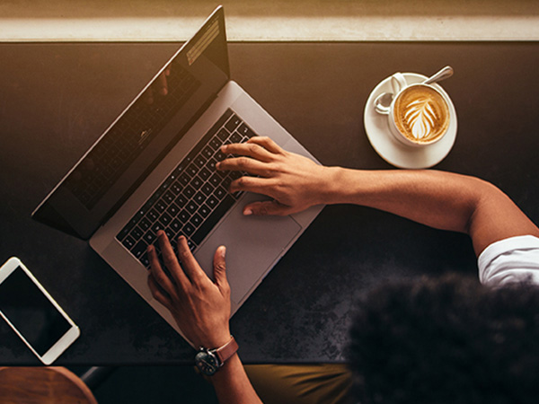 overhead view of a workspace with a laptop and smartphone on a dark desk