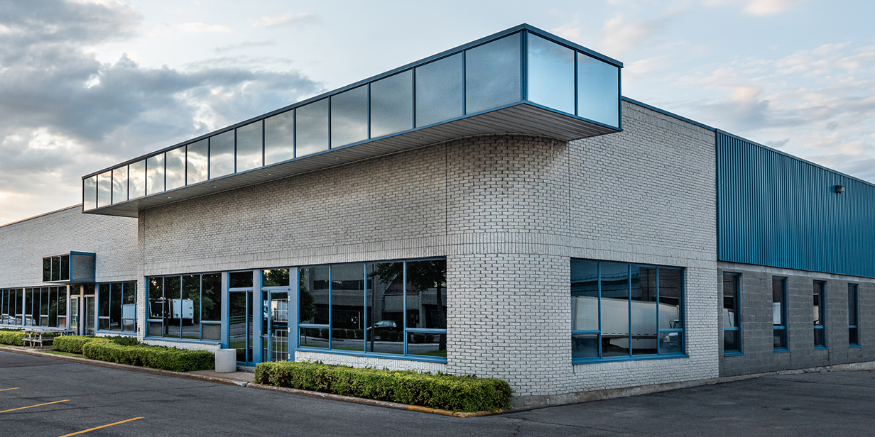 modern industrial building with white brick facade, large glass windows, and blue metal architectural accents – commercial real estate exterior design