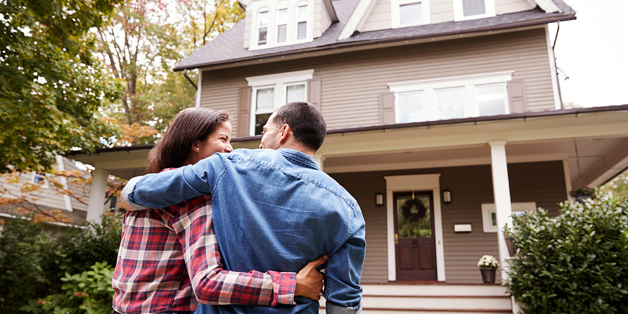 homeowners standing in front of their house, illustrating residential property protection and homeowner risk awareness related to lithium-ion battery safety