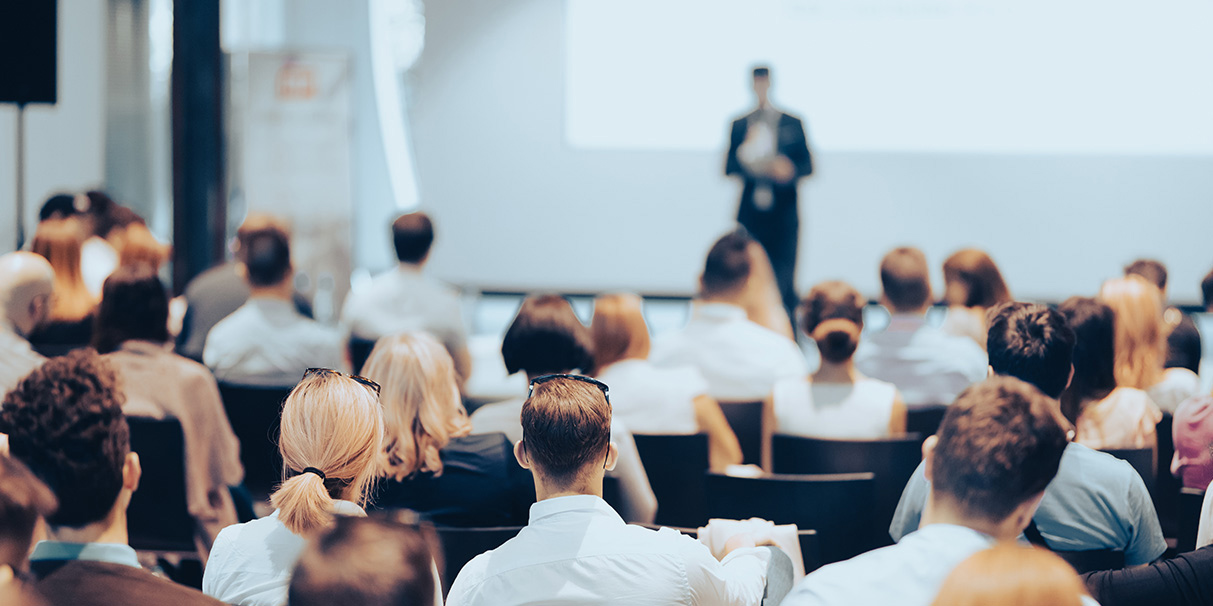 professionals attending a business conference presentation, with a speaker addressing an audience during a corporate seminar focused on industry insights and education