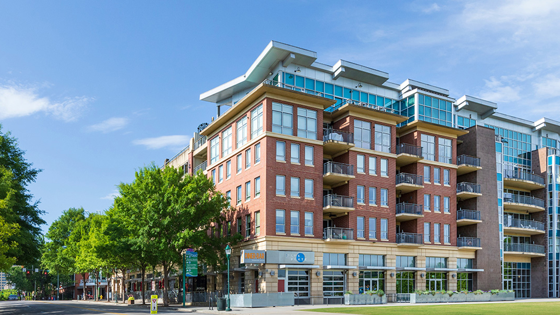 modern multi-story brick apartment building with balconies and ground-floor retail