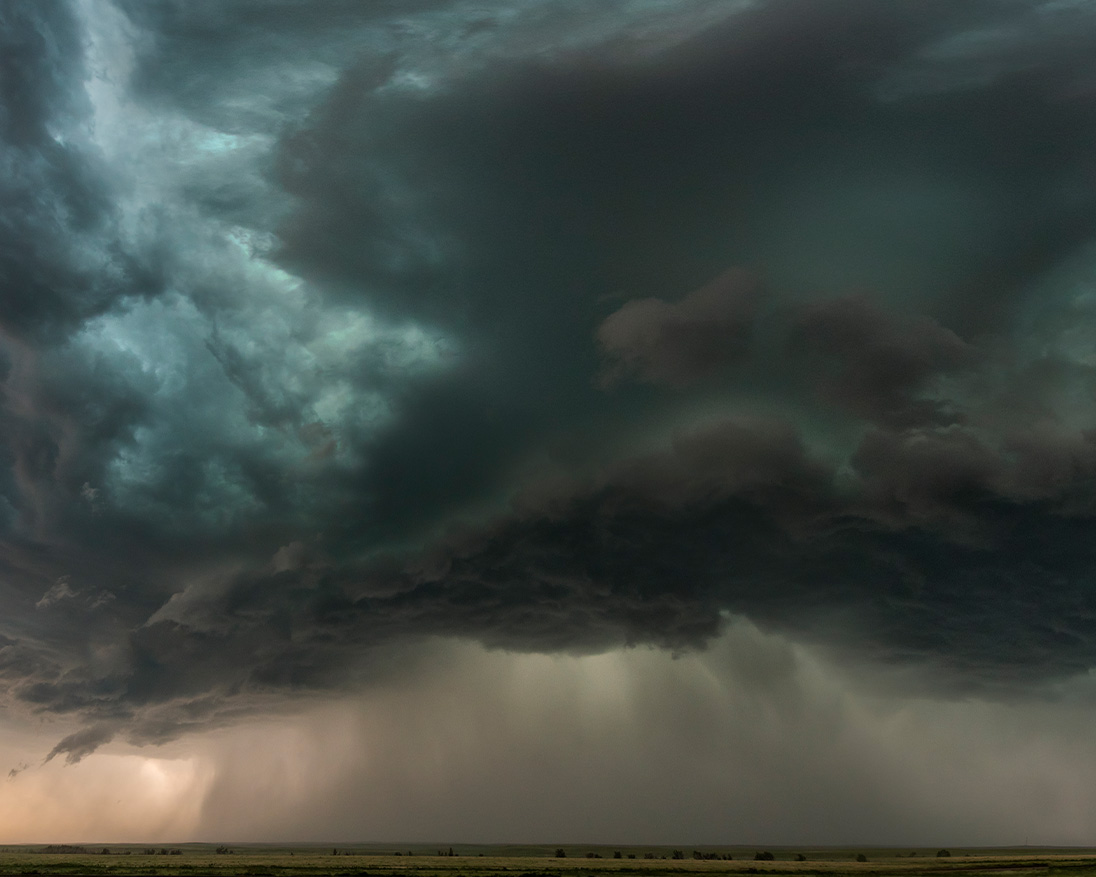 severe thunderstorm with dark rotating clouds and heavy rainfall over a flat rural landscape, showcasing dramatic extreme weather and approaching storm conditions