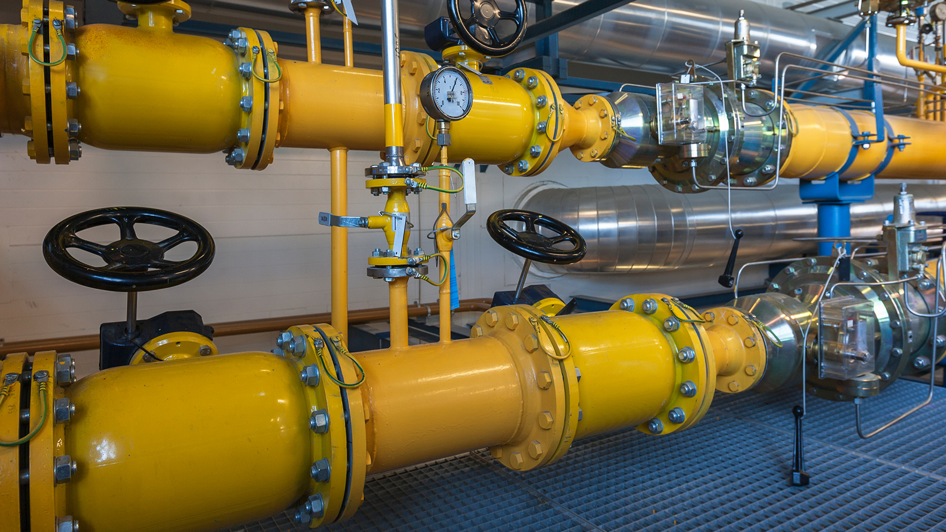 industrial boiler system showing yellow pipes, control valves, and pressure gauges